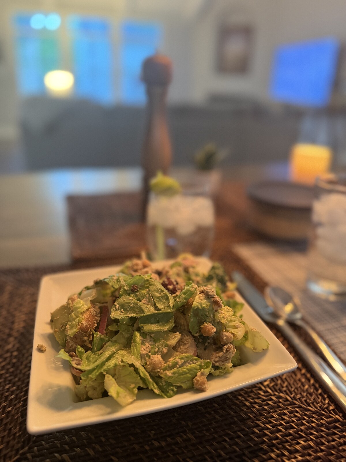 A white plate piled with crisp chopped romaine in a creamy Caesar dressing, topped with golden croutons